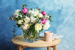 Vase with bouquet of beautiful flowers and cup on table