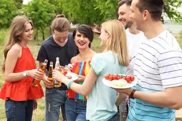 Canvas Print - Young people with bottles of beer and food outdoors. Summer barbecue