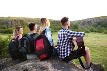 Canvas Print - Group of young people with backpacks and guitar in wilderness. Camping season