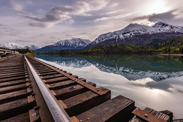 Wall Mural - rail road tracks over lower trail lake with snow caped mountains