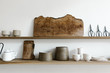 © Nicole Mason/Stocksy - wood shelves of ceramics, scissors and cutting boards on white wall of curated shop