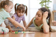 © Oksana Kuzmina - Happy family. Young mother playing ludo boardgame with her children daughters while spending time together at home.