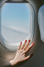 Airplane Window From Inside. 
Female Hand With Red Nails.