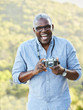 © trinettereed/Stocksy - Portrait of African American Senior man with a vintage film camera laughing outdoors