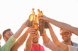 © ManuPadilla - Cheers! Group of happy young people are toasting with bottles of beer in the beach. Celebration concept