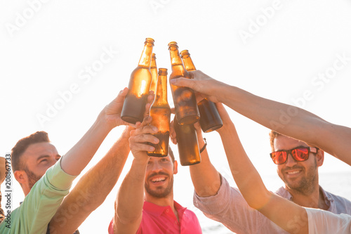 Fotografía Cheers! Group of happy young people are toasting with bottles of beer in the beach