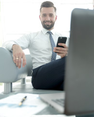 Canvas Print - businessman holding a smartphone and looking at the camera