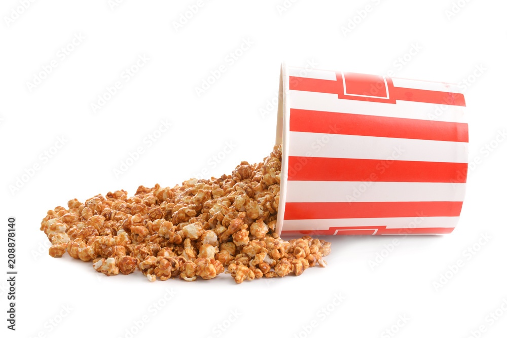 Paper bucket with scattered tasty popcorn on white background