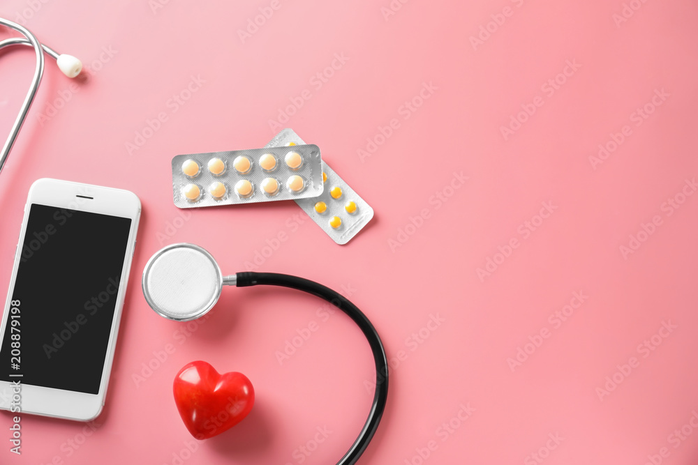 Stethoscope with red heart, pills and phone on color background. Health care concept