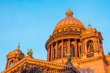 Saint Isaac's Cathedral in the square, in St. Peterburg in the evening on a bright orange sunset sky.