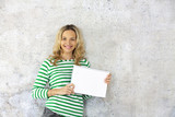 Fototapeta Nowy Jork - young pretty woman with striped pullover holding blank, checkered paper block in the camera.