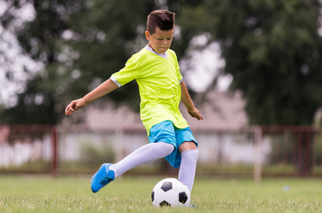 Canvas Print - Boy kicking football on the sports field