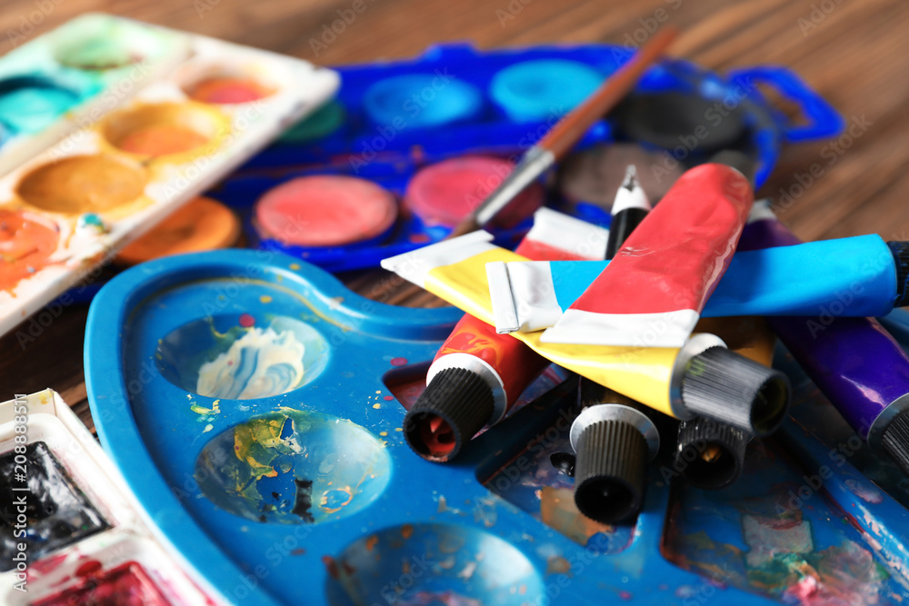 Paint tubes with watercolors palettes on table