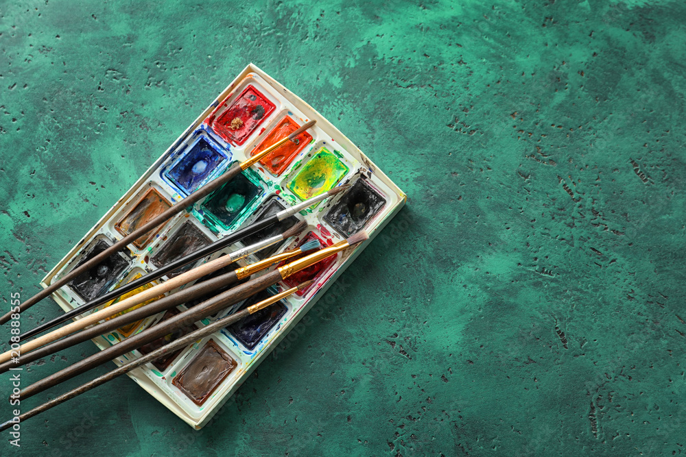Watercolors with paint brushes on color background