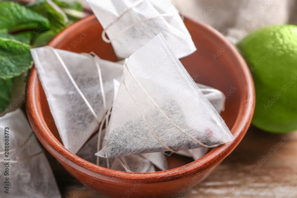 Bowl with tea bags on wooden table
