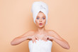 © deagreez - Portrait of unexpected shocked wondered model wrapped in towel with turban on head after shower with big eyes holding towel, afraid of someone, isolated on beige background