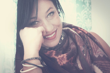 single woman smiling portrait at home in vintage colors and filter. smile and look at the camera with relaxed expression on her face