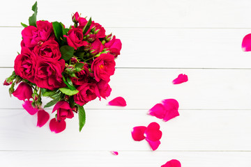 Wall Mural - Home roses in a glass vase on a white wooden table.