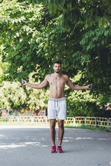 Wall Mural - athletic shirtless young man working out with jumping rope