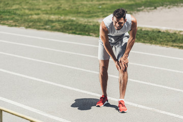 Wall Mural - suffering young runner with leg injury standing on running track