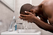 © LIGHTFIELD STUDIOS - side view of young man washing his face at bathroom in morning