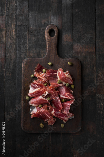 Fotomural Traditional Spanish Jamon Serrano ham, Prosciutto Crudo, Parma ham, Italian antipasto, served with capers