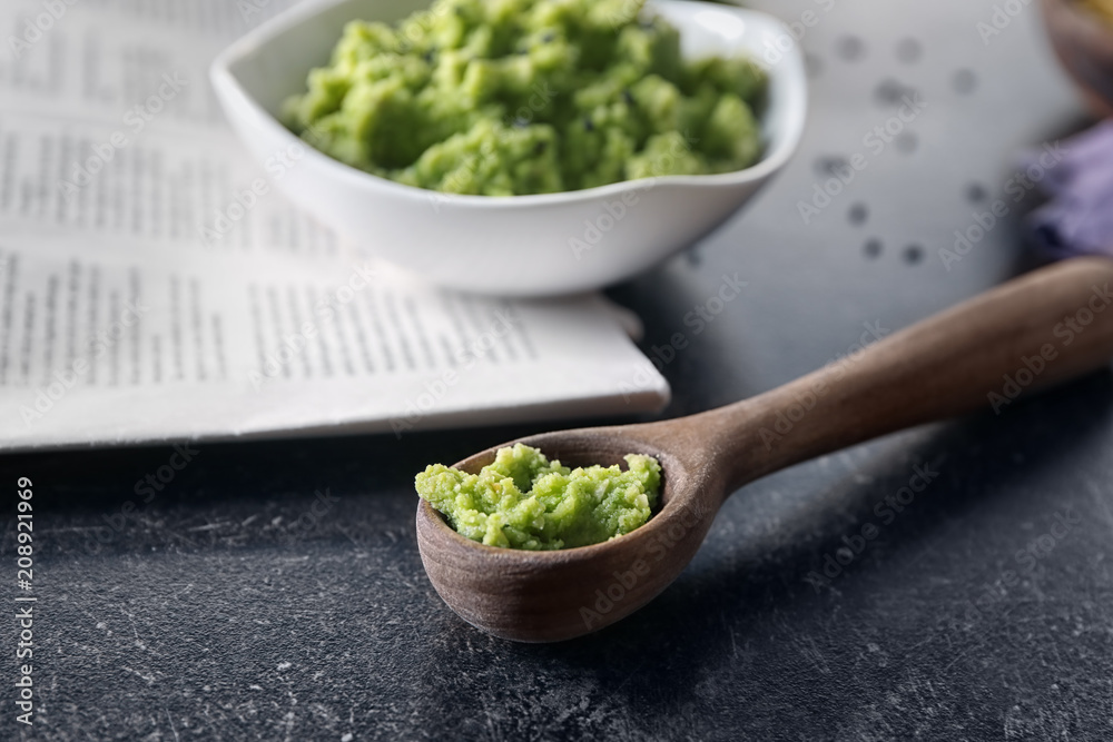 Spoon with delicious guacamole dip made of avocado on table