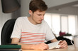 © Pixel-Shot - Young man reading book at home