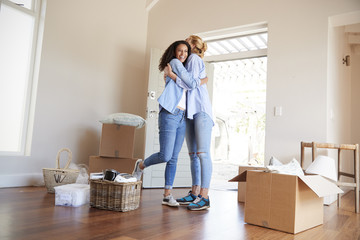 Wall Mural - Female Friends Hugging In Lounge Of New Home On Moving Day