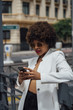 © karrastock - Beautiful Afro hair girl with mobile phone in the streets of Madrid Spain