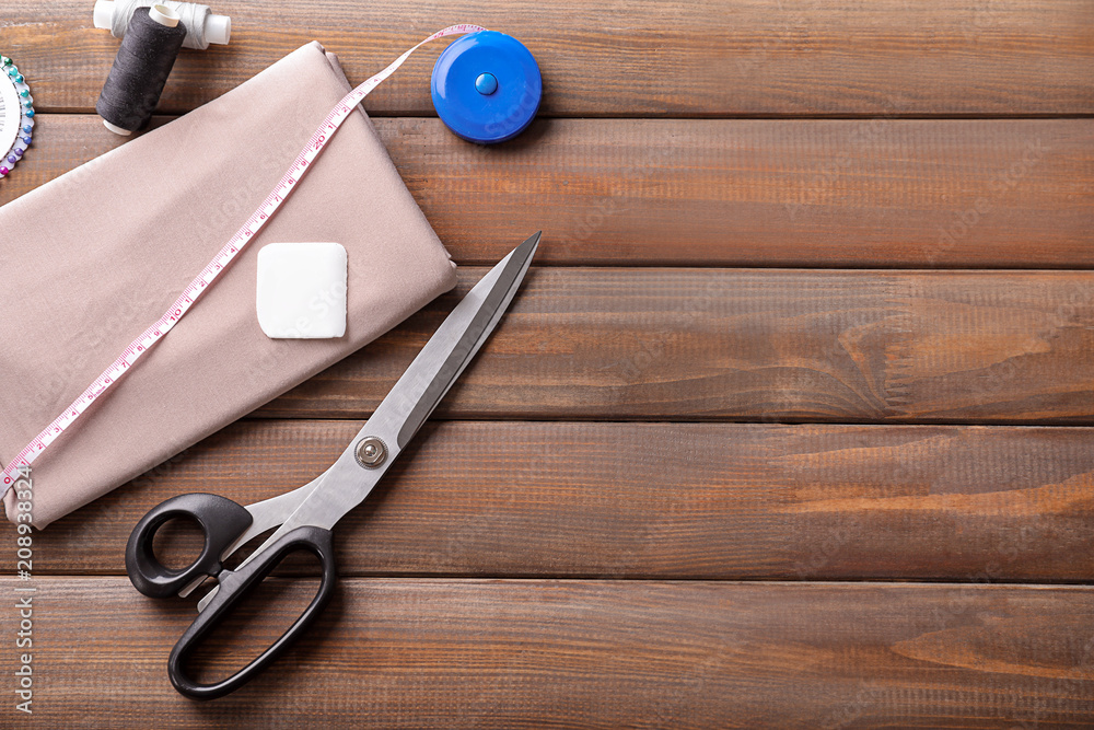 Fabric and sewing accessories on wooden background