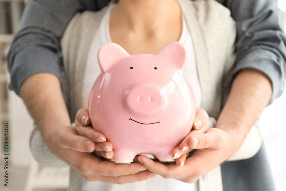 Couple holding piggy bank, closeup. Money savings concept