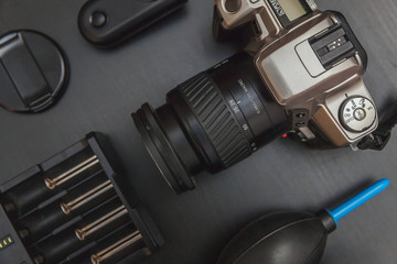 Wall Mural - Top view of work space photographer with dslr camera system, camera cleaning kit, lens and camera accessory on black table background. Hobby journalism photography technology art concept