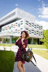 Wall Mural - A pretty girl student stands beside the university