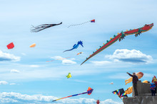 Man Is Holding Huge Flying Kite In Blue Cloudy Sky