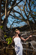 © Vladimir - sexy young bride posing in the middle of tropical trees on a stone wall background in summer