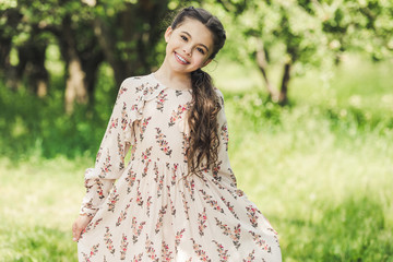 adorable child in stylish dress looking at camera in summer park