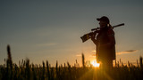 Silhouette of woman hunter. It stands in a picturesque place with a gun at sunset. Sports shooting and hunting concept