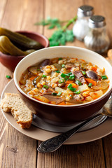 Wall Mural - Traditional Russian soup Rassolnik with pickled cucumbers and pearl barley in bowl on wooden table