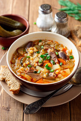 Wall Mural - Traditional Russian soup Rassolnik with pickled cucumbers and pearl barley in bowl on wooden table