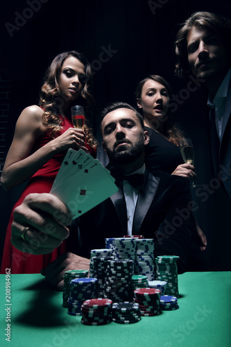 фотография concentrated men and women playing poker in casino