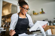 © Joshua Resnick - friendly african american shop assistant using pos terminal to input orders at restaurant