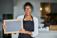 Friendly African American Shop Assistant Holding Blank Chalkboard Slate Sign