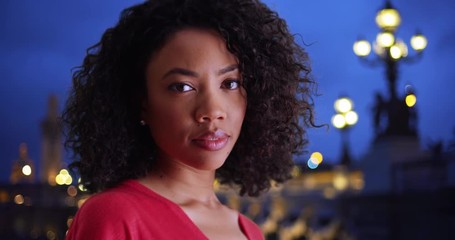 Poster - African millennial woman looking at camera in Paris, France in the evening, Pretty black female with determined look staring at camera by Pont Alexandre III, 4k