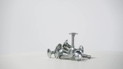 Poster - Bolts rotating on a white wooden table and white background. 