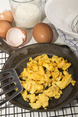 Wall Mural - organic scrambled eggs in a cast iron pan and  whisk in a bowl