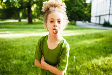 A little curly girl shows her tongue.