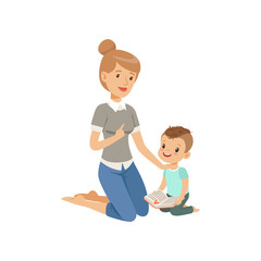 Wall Mural - Elementary teacher having class with her little pupil, boy sitting on the floor and reading a book, preschool education concept vector Illustration