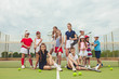 © master1305 - Portrait of group of girls as tennis players holding tennis racket against green grass of outdoor court