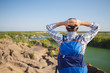 © snedorez - Photo from back of young tourist with backpack with hands behind head against background of mountain landscape, lake